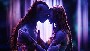 Man sieht Jake Sully und Neytiri als Navi in einem neon-lila Licht. Sie pressen ihre Nasen aneinander. - Foto: IMAGO / Capital Pictures