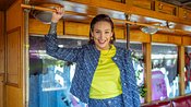 Zu sehen ist Berlin Tag und Nacht Darstellerin Liza Waschke, die in der Serie Milla spielt. Sie steht in einer Art alten Bahn und hält sich an einer Stange oben fest. Sie trägt ein blau gemustertes Anzugset und ein neongrünes Shirt - Foto: RTL II