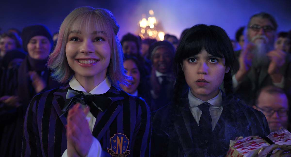 Emma Myers Emma Myers und Jenna Ortega stehen zwischen Nevermore Academy Mitschülern.