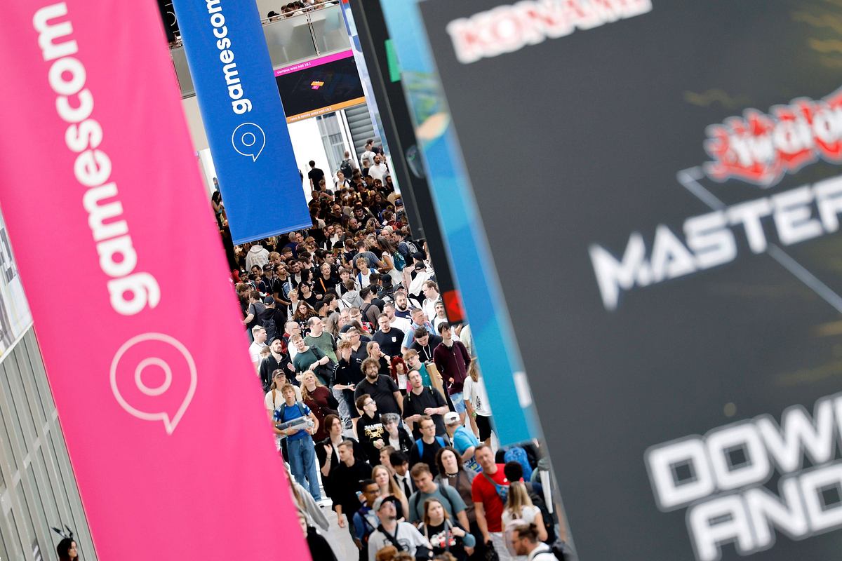 Man sieht ein paar Banner auf der Gamescom. Unter den Bannern sieht man sehr viele Menschen.