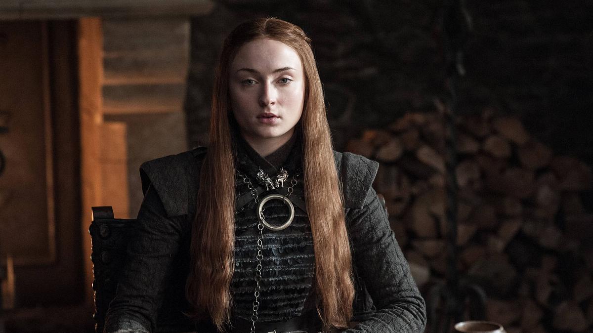 Sophie Turner sitzt in mittelalterlicher Kleidung am Set von „Game of Thrones“.