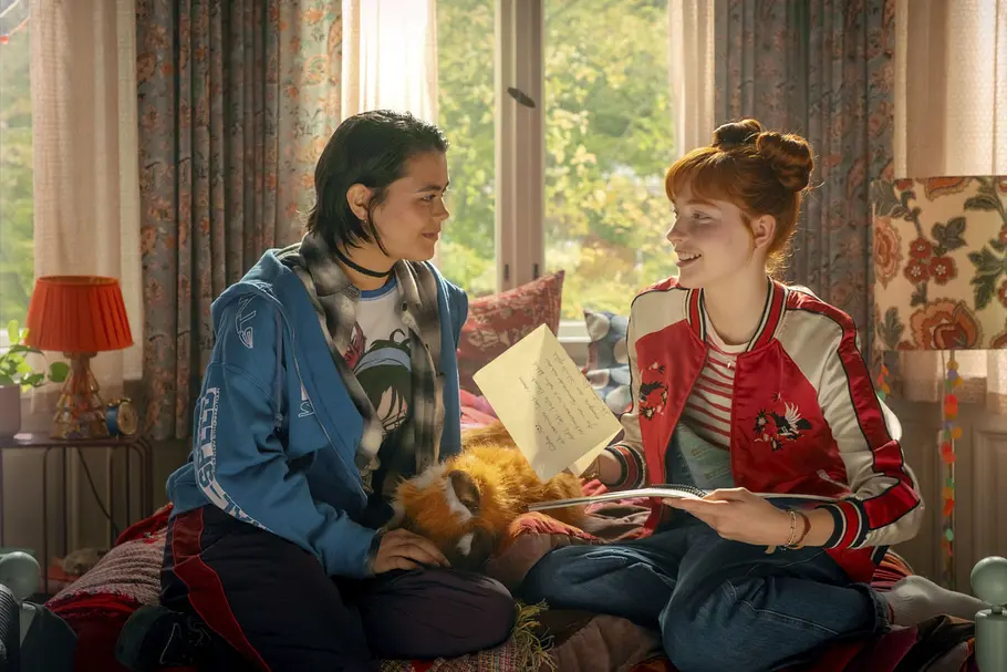 Miriam und Ida sitzen gemeinsam auf einem Bett und lachen