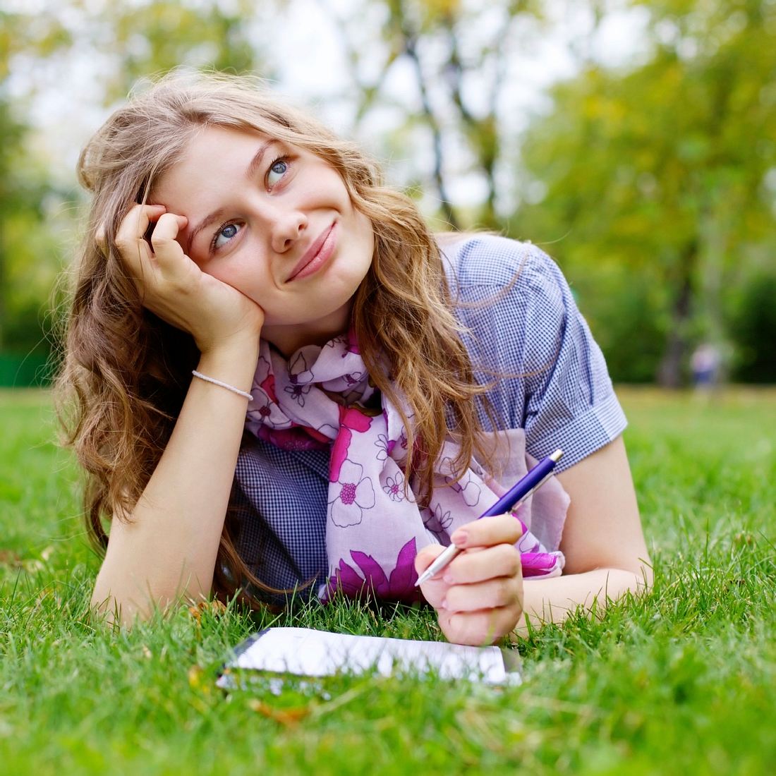 teenage girl making homework in park