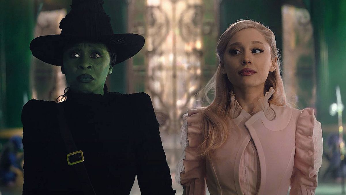 Man sieht Elphaba und Glina im Palast des Zauberers von Oz. Elphaba trägt eine schwarze Hexekluft und Glinda ist in rosa gekleidet.